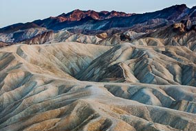 Zabriskie Point. Dans la Vallée de la Mort, les pigments minéraux ont coloré ces dépôts volcaniques. Les sels de fer produisent les couleurs rouges, roses et jaunes. Le mica en se décomposant produit  la couleur verte. Le manganèse produit le violet.