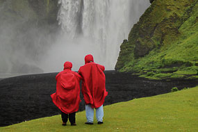 Touristes en tenue « climatique » devant la cascade de Skogarfoss, Islande