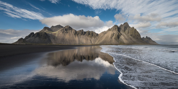 Les Vesturhorn se reflètent sur le sable noir mouillé de la plage, Islande