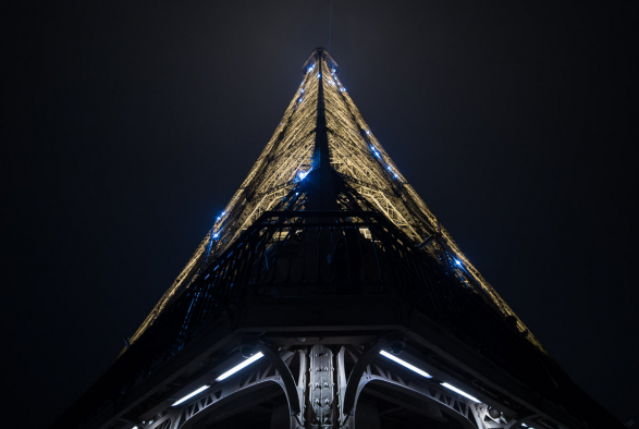 Contre plongée sur le haut de la Tour Eiffel qui scintille la nuit toutes les heures pendant 5 minutes