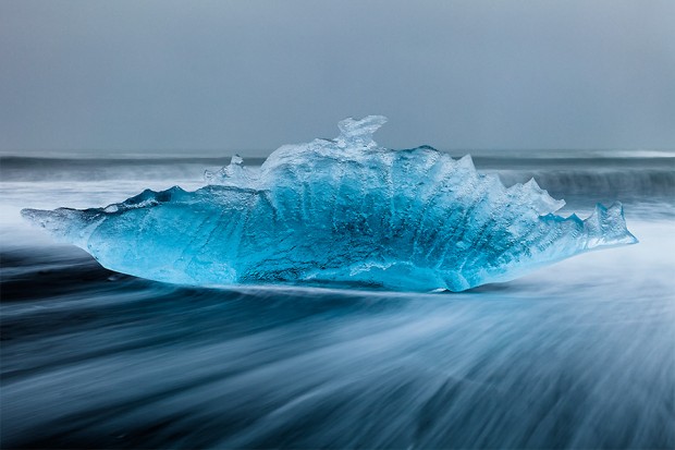 Iceberg errodé par les vagues sur la plage de sable noir à proximité de Jolulsarlon, Islande