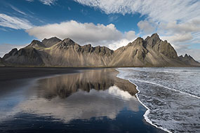 Les Vesturhorn se reflètent sur le sable noir mouillé de la plage, Islande