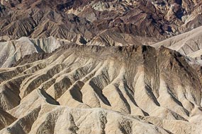 Zabriskie Point. Dans la Vallée de la Mort, les pigments minéraux ont coloré ces dépôts volcaniques. Les sels de fer produisent les couleurs rouges, roses et jaunes. Le mica en se décomposant produit  la couleur verte. Le manganèse produit le violet.