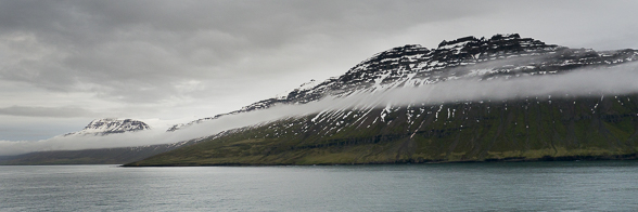 Arrivée dans le Seydisfjordur, les nuages flottent le long des falaises encore enneigées.