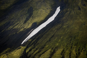 Coulée de neige sur un versant vert et noir dans la réserve de Fjallabak, Islande