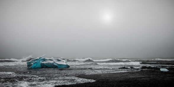Iceberg échoué sur la plage de sable noir et battu par les vagues, en face de la lagune glaciaire du Jokulsarlon, Islande