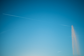 Jet d'eau et traces d'avions dans le ciel bleu parisien.